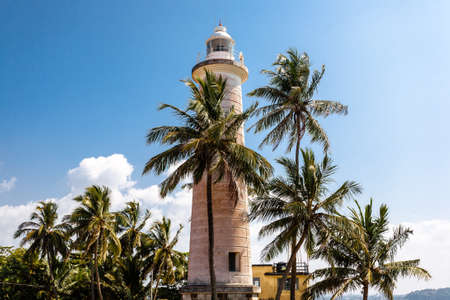 White lighthouse and palm trees on a sunny day in Sri Lanka, Galle Fort.の写真素材