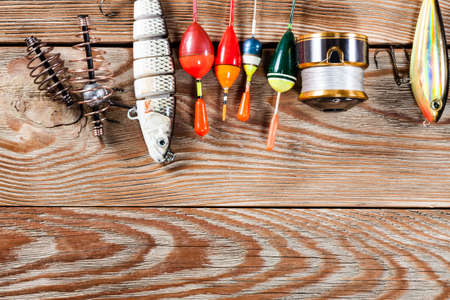View of fishing accessories on white wooden table. Items include fishing reel, wobblers, floats and dock.の写真素材