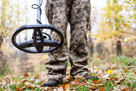 Man with electronic metal detector device working on outdoors background. Close-up photography of searching process.の写真素材