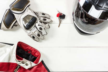 Overhead view of biker accessories placed on white wooden table. Items included motorcycle helmet, gloves, keys and jacket. Motorcycle travel dream concept.の写真素材
