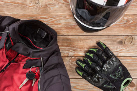 Overhead view of biker accessories placed on rustic wooden table. Items included motorcycle helmet, gloves, keys and jacket. Motorcycle travel dream concept.の写真素材