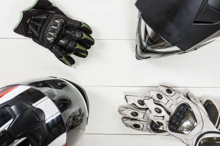 Overhead view of biker accessories placed on white wooden table. Items included motorcycle helmet and gloves. Motorcycle travel dream concept.の写真素材