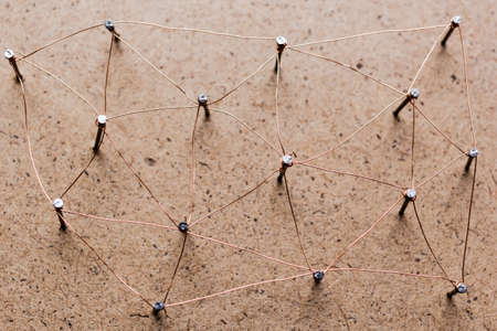 Linking entities. Network, networking, social media, connectivity, internet communication abstract. A small network connected to a larger network. Web of threads on cork board.の写真素材