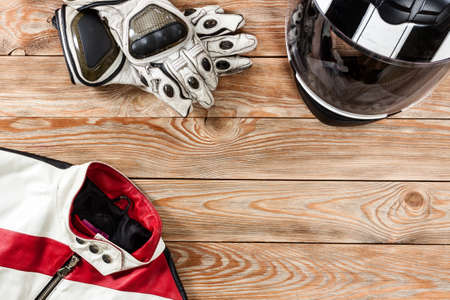 Overhead view of biker accessories placed on rustic wooden table. Items included motorcycle helmet, gloves and jacket. Motorcycle travel dream concept.の写真素材
