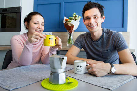 Romantic couple. Beautiful young loving couple having fun while drinking coffee at home.の写真素材