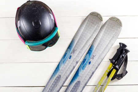 Overhead view of ski accessories placed on rustic white wooden table. Items included ski, goggles, helmet and ski sticks. Winter sport leisure time concept.の写真素材