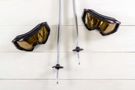 Overhead view of ski accessories placed on rustic white wooden table. Items included gloves and ski...