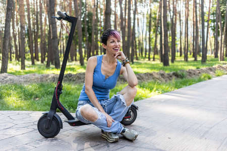 Cool attractive woman with pink hair, enjoys riding an electric scooter. Eco friendly transport,...