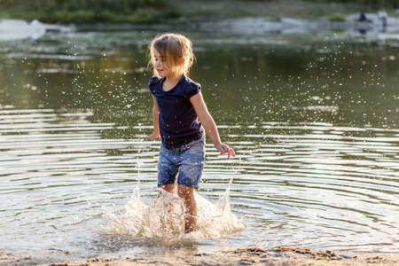 Little girl having fun in summer, jumping in river.の写真素材