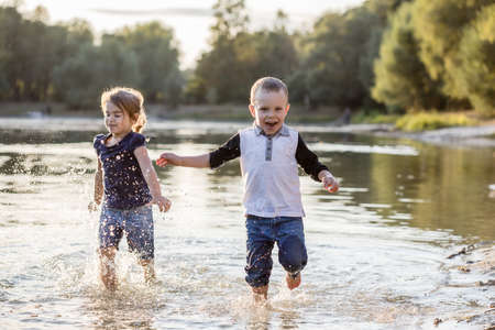 Family and friends summer vacation. Happy kids kids running through water in summer over sunset.の写真素材