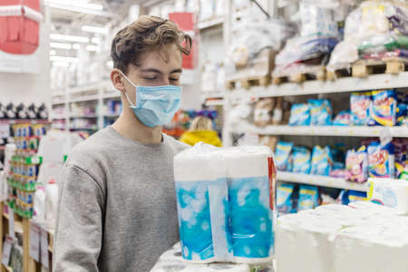 Young man wearing disposable medical mask shopping in supermarket during coronavirus pneumonia outbreak. Protection and prevent measures while epidemic time. Covid-19 personの写真素材