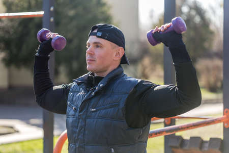 Outdoor Workout lifestyle concept. Young man doing exercises outdoor. Muscular athlete exercising...