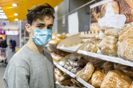 Young man wearing disposable medical mask shopping in supermarket during coronavirus pneumonia...