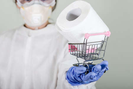 Doctor in protective wear holding toilet paper.の写真素材