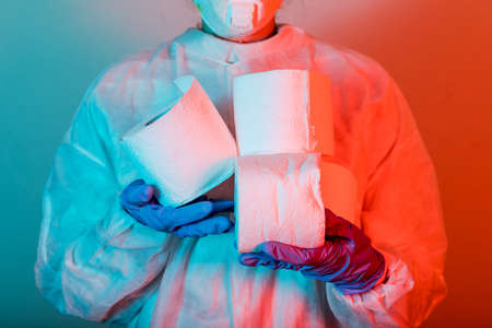Doctor in protective wear holding toilet paper.の写真素材
