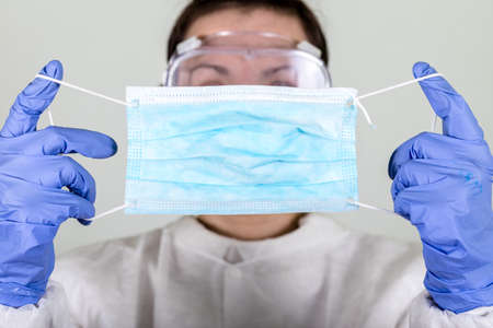 Doctor in protective wear holding special defence mask from Coronavirus COVID-19 analyzing.Vaccine from, flu, coronavirus, ebola.の写真素材