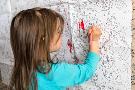 Covid-19 Coronavirus and Learning from home.  Cute little girl coloring on her wall at home. Quarantine and Social distancing concept.の写真素材