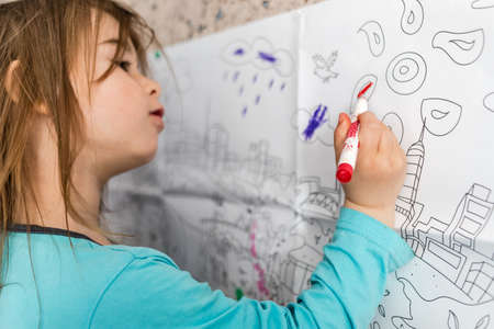 Covid-19 Coronavirus and Learning from home.  Cute little girl coloring on her wall at home. Quarantine and Social distancing concept.の写真素材