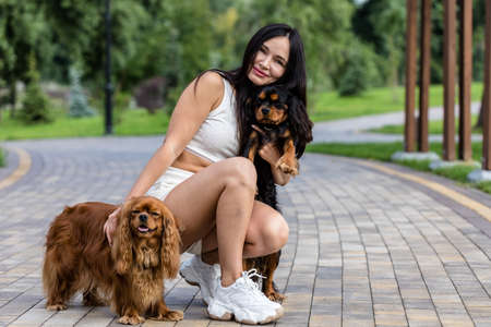 Attractive woman relaxing with her two adorable dogs. Two cavalier king charles spaniel dogs.の写真素材