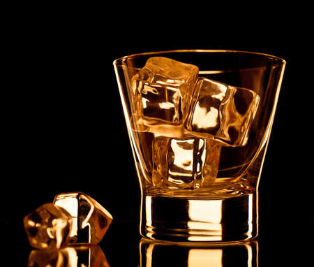Empty whiskey glass with ice cubes on black backgroundの写真素材