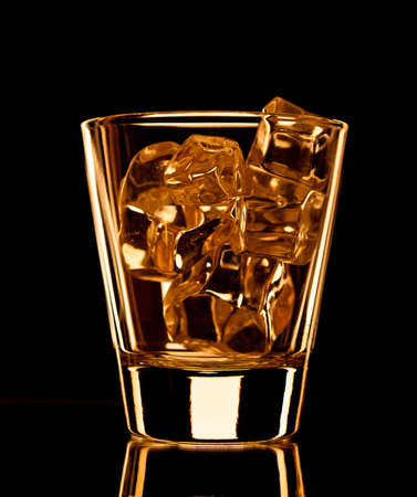 Empty whiskey glass with ice cubes on black backgroundの写真素材