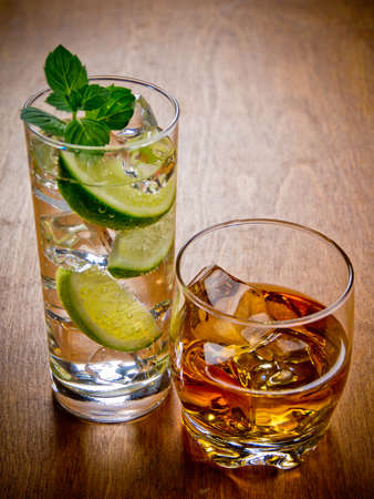 Two glasses of alcohol beverages, gin and tonic and whiskey on the rocks