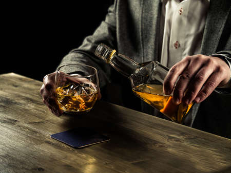 Businessman pouring whiskey in his glassの写真素材