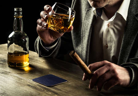 Well-dressed man with a cigar drinking whiskeyの写真素材