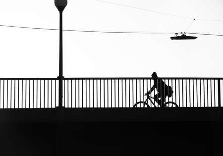 Silhouette image of a cyclist riding across the bridge early in the morning