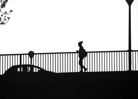 Silhouette image of a woman walking on the bridge early in the morning