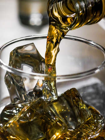 Close-up image of whisky being poured from a bottle into a glassの写真素材
