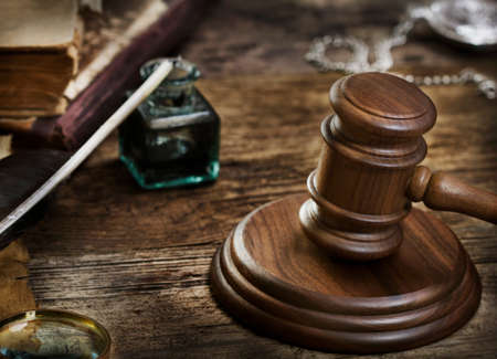 Wooden gavel on grunge wooden background with quill pen, inkwell, and booksの写真素材