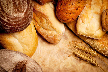 assortment of baked bread with wheat on vintage paper background