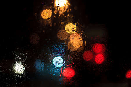 Rain drops on window with road light bokeh, rainy season abstract background,water drop on the glass, night storm raining car driving concept.の写真素材