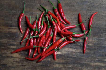 Many red peppers on a wooden background