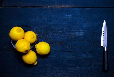 lemons and knife on cutting board on wooden tableの写真素材