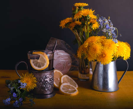 cup holder tea with lemon, sugar and dandelions flowers
