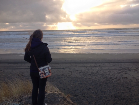 A woman looking out to sea as the sun sets in Westport WAの素材