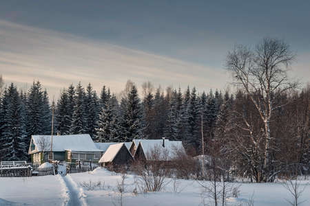 Fabulous winter landscape in a village in the north of Russia - a bright sun, white snow, cozy wooden housesの写真素材