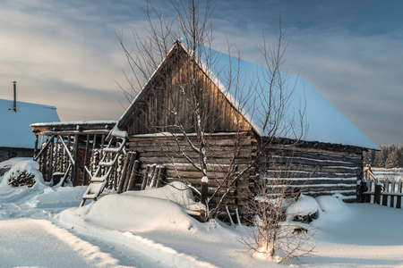 Fabulous winter landscape in a village in the north of Russia - a bright sun, white snow, cozy wooden housesの写真素材