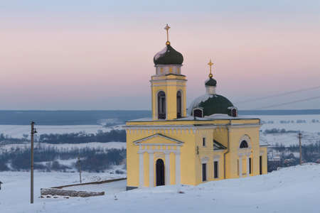 Russian Orthodox church against the sunset sky in the middle of a snowy field in winterの写真素材