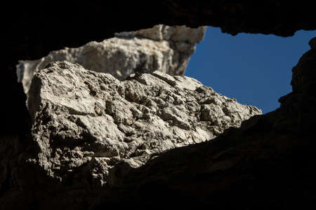 Cleft in the rock formed a massive window through which one can see the blue sky and stonesの写真素材