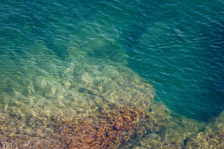 Outskirts of the Black Sea coastline, rocky stones go into the water. Blue-green water of the sea...