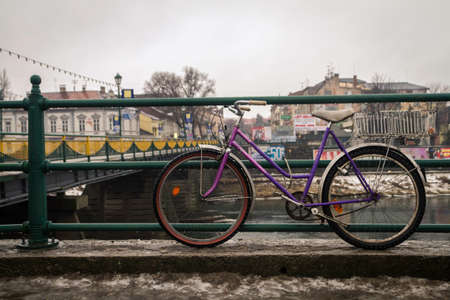 Purple bicycle parked on the bridge of the old European city in the rainの写真素材
