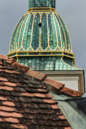 Detail of the main tower in Bratislava, Slovakia. Green roof with gold elements on a red tile roofの写真素材