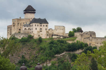 An ancient medieval castle on the hill light among green trees in the city of Trencin in Slovakiaのeditorial素材
