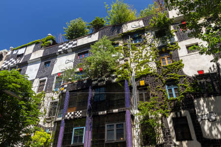 Colorful house of the Austrian artist Friedensreich Hundertwasser in Vienna in the summer under the bright blue sky and green trees nearのeditorial素材