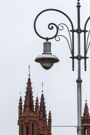 Beautiful city lantern on a background of red brick towers of the Catholic Cathedral of St. Anne in Vilnius, Lithuaniaの写真素材