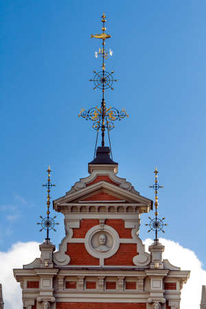 Golden spire with a compass and fish on top on the roof of the House of the Blackheads in Riga, Latviaの写真素材