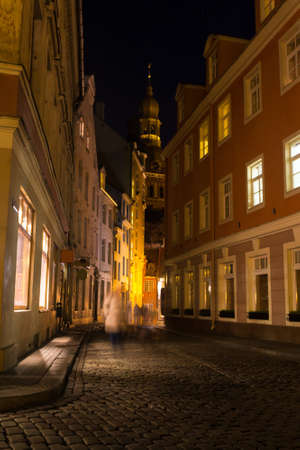 Covered with paving stones street in Old Riga, Latvia, at night. Street illuminated by beautiful bright lightsの写真素材